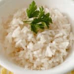 closeup of white rice in a bowl with a sprig of parsley