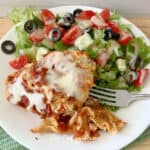 a plate with a piece of slow cooker lasagna and a salad and a fork