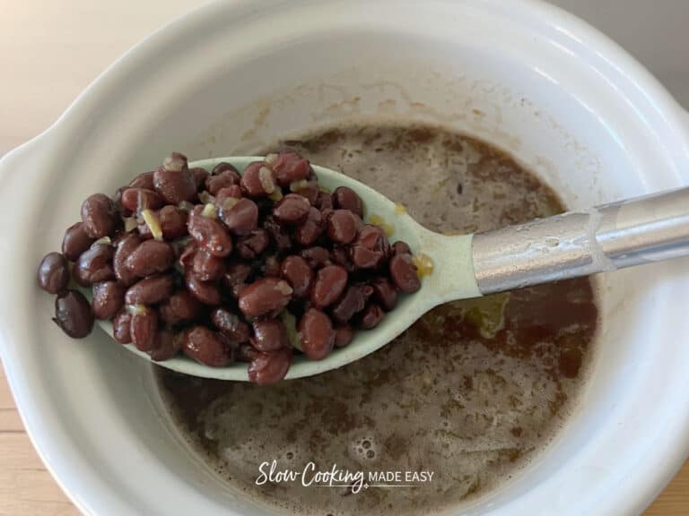 bbq black beans in a slow cooker with a spoonful of beans hovering above the rest